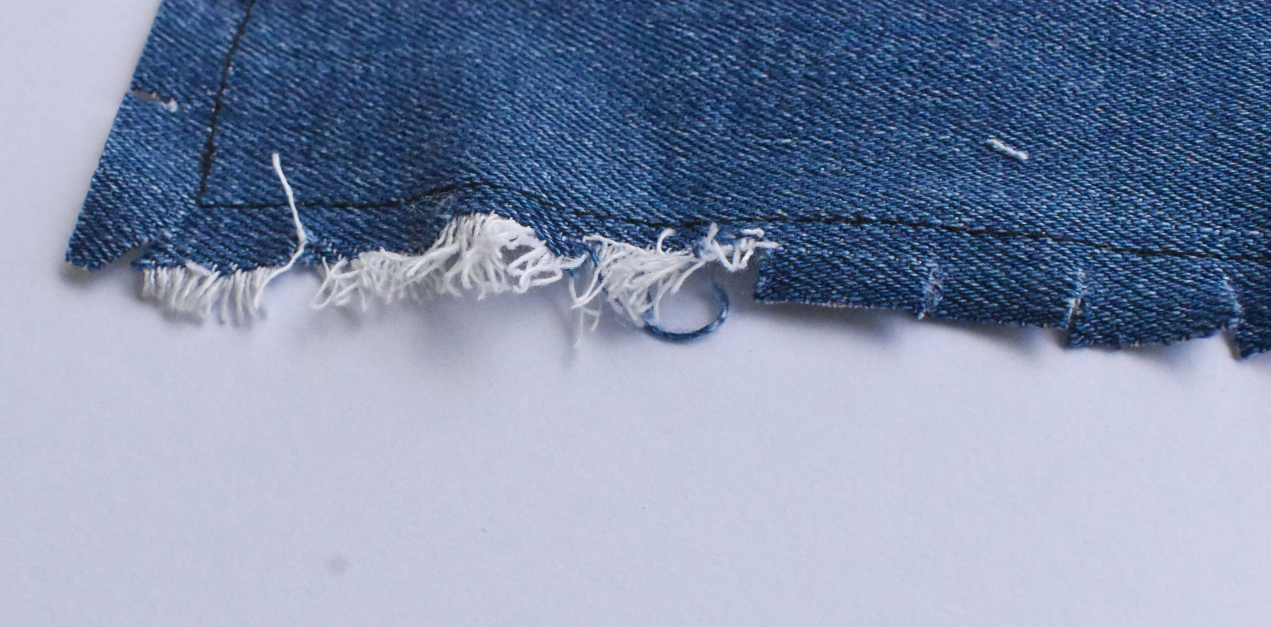 fraying the edges of the denim fabric piece